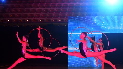 Cinco alunas a realizar um esquema de ginástica rítmica