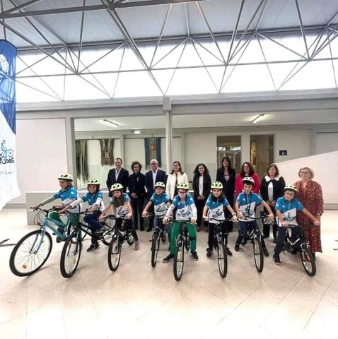 Foto com 8 alunos, com as suas bicicletas. Atrás as entidades, do que se destaca o Secretário de Estado da Juventude e Desporto